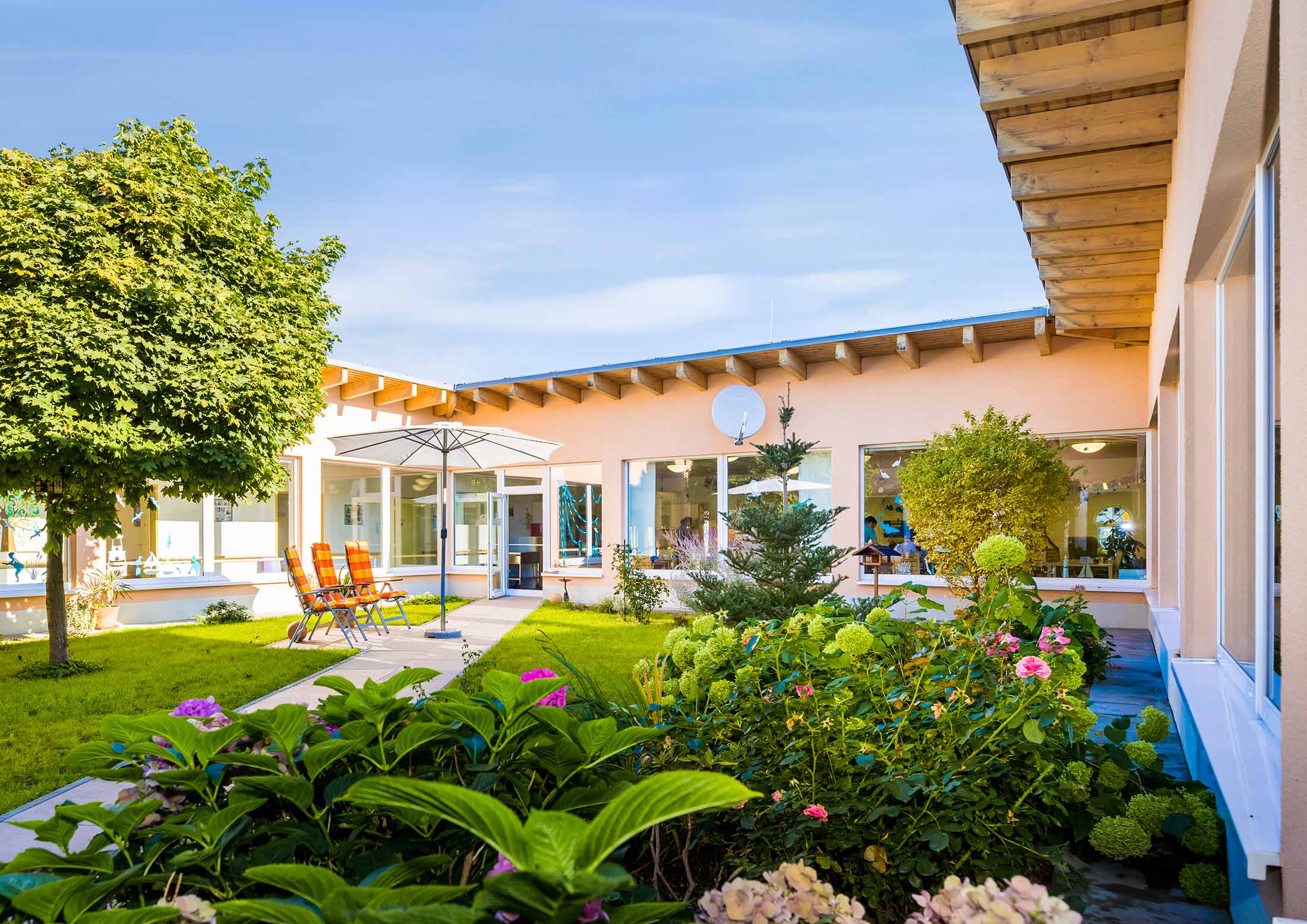 Gartenanlage im Innenhof mit Hortensien und Sitzplätzen