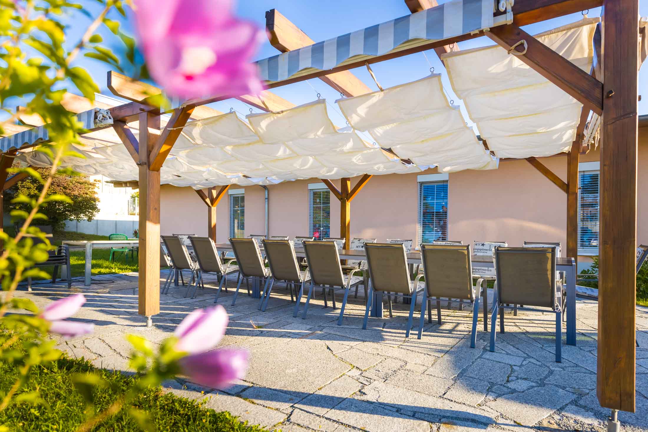 Beschattete Terrasse mit langer Tafel unter der Pergola